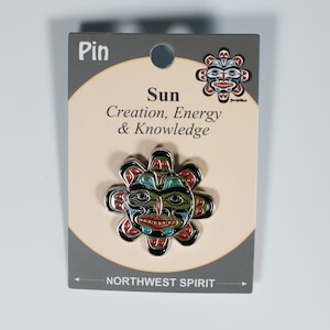 Peut inclure: Une épingle Northwest Spirit représentant un soleil stylisé avec un visage. Le soleil est noir, rouge, vert et bleu. Le texte sur la carte indique "Pin, Sun, Creation, Energy & Knowledge, Northwest Spirit".