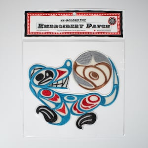 以下が含まれることがあります： 青い、赤い、白いスタイリッシュな動物が茶色と灰色の球体を持っている刺繍パッチ。パッチは、赤い、白い、黒いヘッダーが「Golden Top Embroidery Patch」と表示されている透明なプラスチック袋に入っています。
