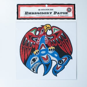 May include: Embroidered patch depicting a red and blue eagle with a yellow beak and black eyes, holding a blue and white orca in its talons. The patch is surrounded by a black border and features the text "Golden Top Embroidery Patch" in white lettering.