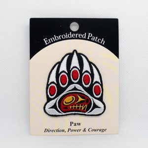 May include: Embroidered patch featuring a white and black bear paw print with red accents. The paw print has a stylised face inside. The text on the card reads "Embroidered Patch" and "Paw Direction, Power & Courage".