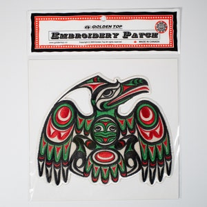 Puede incluir: Parche bordado con un diseño de águila estilizado en verde, rojo y negro. El parche está etiquetado como "Golden Top Embroidery Patch" y "Hecho en Canadá".