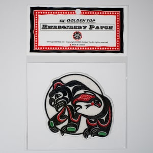 Peut inclure: Patch brodé représentant un ours stylisé noir et rouge sur fond blanc. Le patch est emballé dans un sac en plastique transparent avec une étiquette rouge et blanche qui indique "Golden Top Embroidery Patch".
