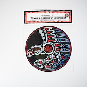 Può includere: Una toppa rotonda nera ricamata con un design di aquila bianco e blu. L'aquila ha un viso rosso e tiene un pesce nelle sue zampe. La toppa è etichettata "Golden Top Embroidery Patch".
