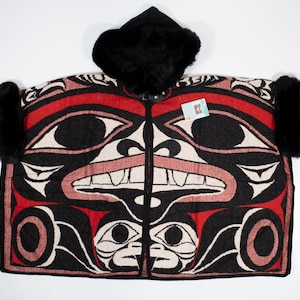 May include: A black hooded poncho with red, black, and white patterned designs. The poncho features a traditional Native American design with a stylized face and geometric shapes.