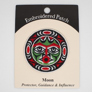 May include: Embroidered patch featuring a stylised image of a face in red, white, green and black. The text "Embroidered Patch" is at the top of the card and "Moon Protector, Guidance & Influence" is at the bottom.