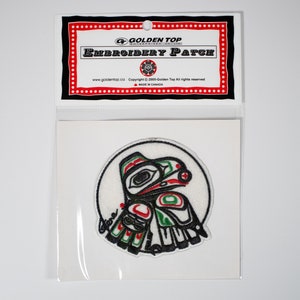 May include: A white embroidered patch featuring a stylised bird design in black, red and green. The patch is circular and has a white background. The text "Golden Top" is printed on the packaging.