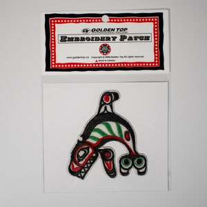 May include: An embroidered patch featuring a stylized black, red, and green orca whale design. The patch is packaged on a white card with a red and black border and the text "Golden Top Embroidery Patch".