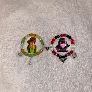 May include: Two beaded bracelets with character images. One bracelet features green, yellow, and clear beads with a guitar charm and a cartoon character. The other bracelet has red, black, and white beads with a bat charm and a cartoon character.