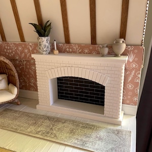 May include: A white brick fireplace with a black brick interior. The fireplace is decorated with a potted plant and two ceramic vases. A patterned rug sits in front of the fireplace.