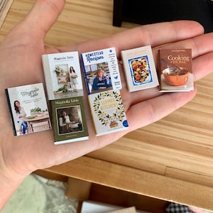 May include: A collection of six miniature cookbooks with various titles, including "Magnolia Table", "Homestead Recipes", "Lost Kitchen", "Summer Kitchens", and "Cooking at Home".