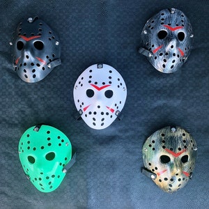 以下が含まれることがあります： さまざまなデザインのハロウィンマスクが5つあります。 マスクはすべて白で、黒いディテールと赤いアクセントが付いています。 マスクはすべてプラスチック製で、目に穴が開いています。