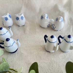 May include: Set of nine ceramic salt and pepper shakers in the shape of owls and teapots. The shakers are painted in white and blue with floral designs.