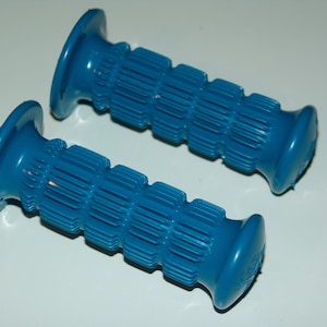 Puede incluir: Dos puños de manillar azules. Cada puño tiene un diseño acanalado para un mejor agarre y un extremo ensanchado. Los puños son de un color azul vibrante y parecen estar hechos de un material plástico o de goma duradero.