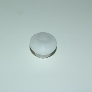 Puede incluir: Un pequeño componente de mueble de plástico blanco con una parte superior redondeada y una base cilíndrica. El componente tiene un centro hueco y está diseñado para encajar en un orificio correspondiente. El objeto es probablemente un tapón.