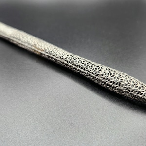 Pode incluir: Uma caneta de prata com um design de padrão geométrico.