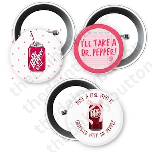 May include: Three white button pins with black metal backings. One pin features a pink Dr. Pepper can with the text "Dr Pepper Slut". Another pin says "I'll take a Dr. Pepper!" in pink. The third pin says "Just a girl who is obsessed with Dr Pepper".
