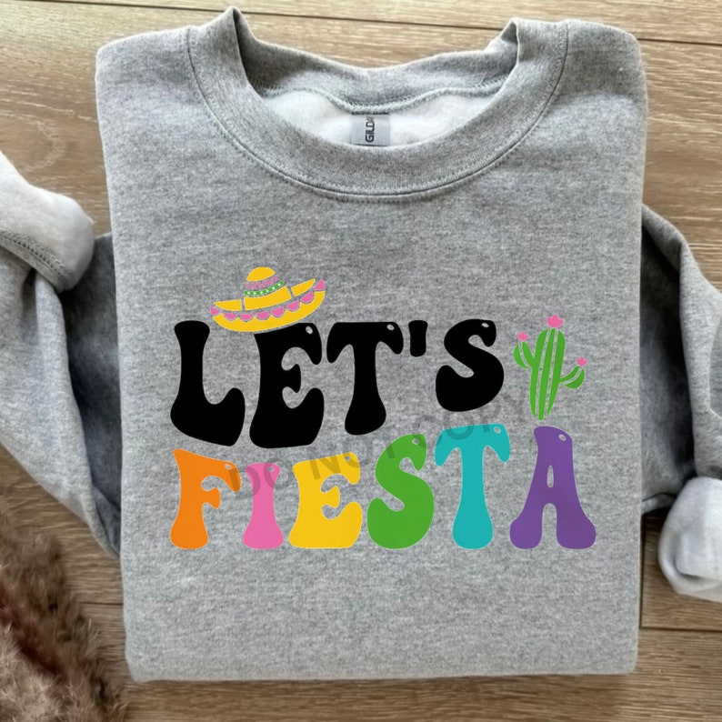 May include: Gray sweatshirt with the text "Let's Fiesta" in colorful letters. A sombrero and cactus are above the text.
