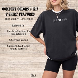 May include: Black Comfort Colors T-shirt with "POM mom" text. The shirt features a relaxed fit and is made of high-quality, garment-dyed 100% cotton. The shirt has pre-shrunk cotton for size retention and is made with US-grown cotton.