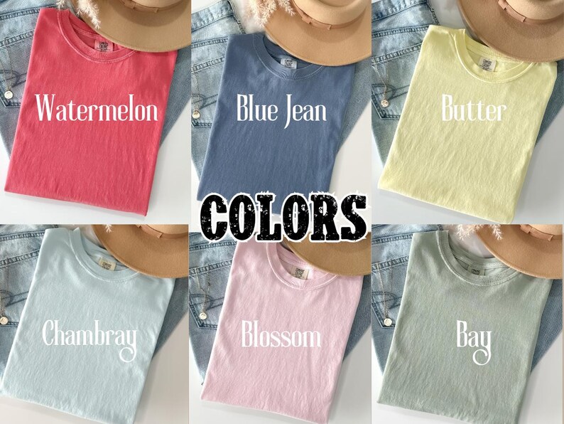 May include: A collection of six t-shirts in various colors: Watermelon, Blue Jean, Butter, Chambray, Blossom, and Bay. Each shirt is folded and displayed with a hat and denim jeans. The word "COLORS" is in the center.