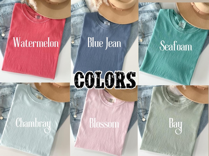 K&ouml;nnte beinhalten: Sechs einfarbige T-Shirts in verschiedenen Farbt&ouml;nen wie Wassermelone, Blue Jean, Seafoam, Chambray, Blossom und Bay. Jedes Shirt ist gefaltet und wird mit einem Hut und Jeans pr&auml;sentiert. Das Wort "COLORS" ist in der Mitte zu sehen.