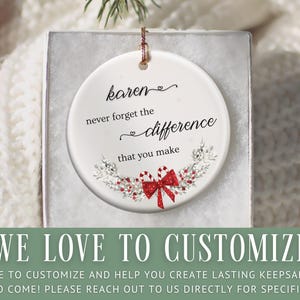 May include: A white ceramic ornament with the text "karen never forget the difference that you make." The ornament has a red bow and candy cane design. The bottom of the image has the text "WE LOVE TO CUSTOMIZE!"
