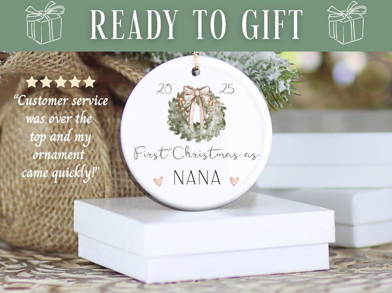 Puede incluir: Adorno navide&ntilde;o de cer&aacute;mica blanca con dise&ntilde;o de corona, el texto "First Christmas as NANA" y los a&ntilde;os 20 y 25. Las palabras "READY TO GIFT" est&aacute;n en la parte superior. El adorno est&aacute; sobre una caja blanca.