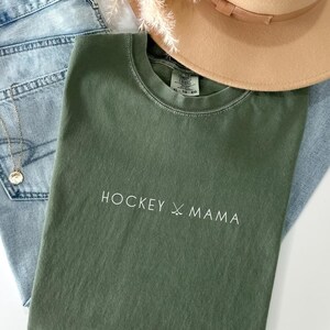 May include: A green t-shirt with the text "HOCKEY X MAMA" in white lettering.