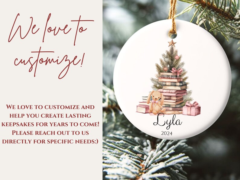 May include: A white ceramic Christmas ornament with a watercolor illustration of a Christmas tree decorated with books and a small bunny. The ornament is personalized with the name "Lyla" and the year "2024".