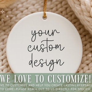 Op de afbeelding: Ronde witte keramische ornament met de tekst "your custom design" in zwart script. Het hangt aan een gouden touwtje. De tekst "WE LOVE TO CUSTOMIZE!" staat onderaan.