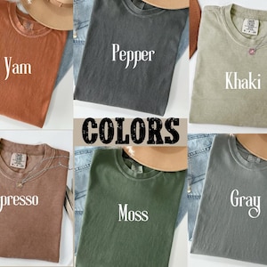 K&ouml;nnte beinhalten: Eine Sammlung von T-Shirts in verschiedenen Farben, darunter Yam, Pepper, Khaki, Espresso, Moss und Grau. Jedes Shirt hat eine andere Farbe und der Farbname ist auf dem Shirt aufgedruckt.