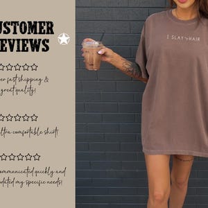 May include: A brown oversized t-shirt with the text "I SLAY HAIR" printed on the front. The shirt is being modeled by a person with a tattoo on their arm. The background is a brick wall.