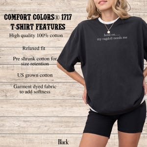 May include: Black Comfort Colors T-shirt with the text "hold on..... my ragdoll needs me". The shirt features a relaxed fit and is made of 100% US grown cotton. The image also shows black shorts.