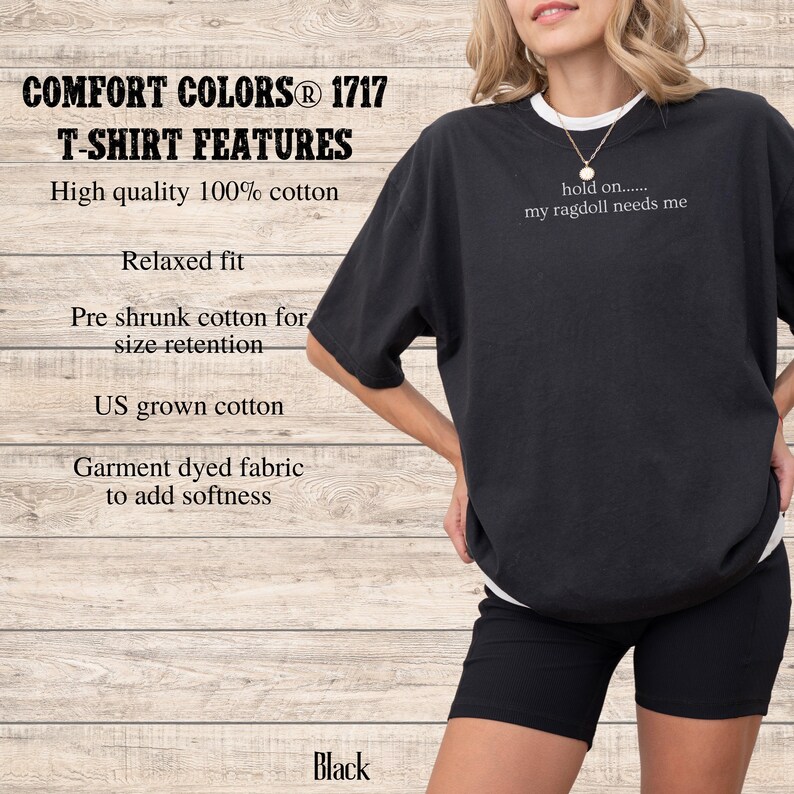 May include: Black Comfort Colors T-shirt with the text "hold on..... my ragdoll needs me". The shirt features a relaxed fit and is made of 100% US grown cotton. The image also shows black shorts.