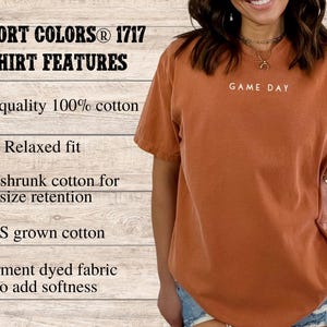 May include: A rust-colored t-shirt with a relaxed fit. The shirt is made of 100% cotton and features the text "GAME DAY" printed on the front.