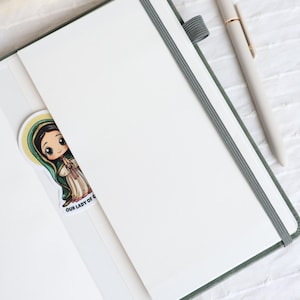 Inside view of sage green Catholic prayer journal with lined pages, elastic closure, inner pocket, ribbon bookmark, and matching pen for Bible study notes