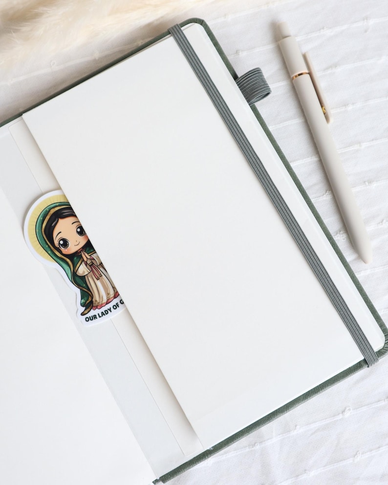 Inside view of sage green Catholic prayer journal with lined pages, elastic closure, inner pocket, ribbon bookmark, and matching pen for Bible study notes
