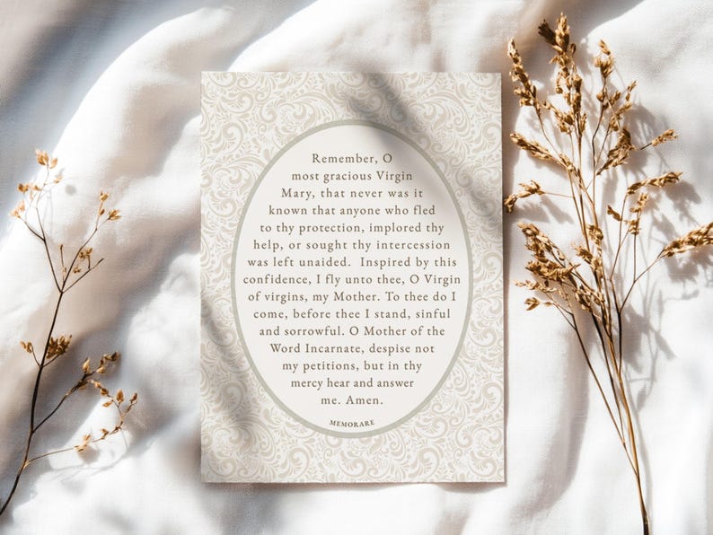 Memorare Prayer printable Catholic art card lying on soft white fabric with dried florals — vintage-style Marian devotion wall art digital download for Catholic home decor.
