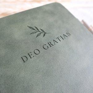 Close up of sage green Catholic journal engraved Deo Gratias with botanical design, personalized prayer journal gift for women