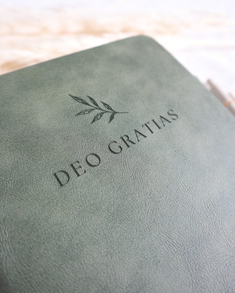 Close up of sage green Catholic journal engraved Deo Gratias with botanical design, personalized prayer journal gift for women