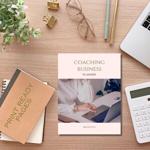 May include: A pink and white printable coaching business planner with the text "Coaching Business Planner" and "Montar Dion" on the cover. The planner features a woman working on a laptop.