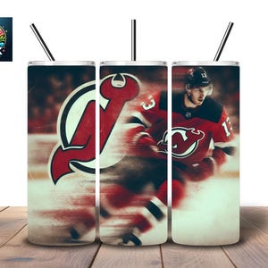 May include: A set of three stainless steel tumblers with black straws. Each tumbler features a design related to the New Jersey Devils hockey team. The designs include the team logo and a player in action.