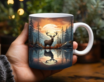 May include: White ceramic mug featuring a scenic landscape with a deer standing in a lake, reflecting the image of the deer and the surrounding forest and mountains. The background shows a sunset with orange and yellow hues.