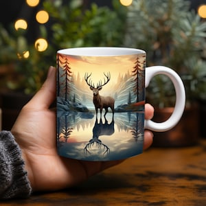 May include: White ceramic mug with a colorful illustration of a deer standing in a lake with a forest background. The deer is reflected in the water.