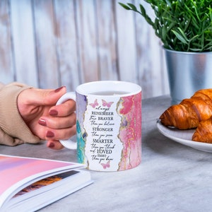 May include: White ceramic mug with a pink, green, and gold watercolor design and the text "always remember you are braver than you believe stronger than you seem smarter than you think and more loved than you know".