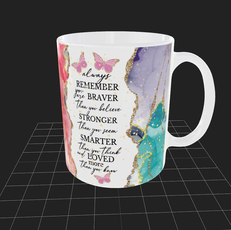 May include: White ceramic mug with a colorful abstract design and gold glitter accents. The mug features a motivational quote: "always REMEMBER you are BRAVER than you believe STRONGER than you seem SMARTER than you think and LOVED more than you know".