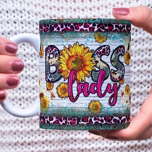 May include: White ceramic mug with a colorful design featuring a sunflower, leopard print, and the text "Boss Lady".