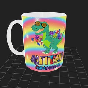Puede incluir: Una taza de cer&aacute;mica blanca con un fondo de arco&iacute;ris colorido y un dinosaurio verde con gafas de sol. El dinosaurio sostiene piezas de rompecabezas y el texto "AUTISM AWARENESS" est&aacute; escrito debajo.