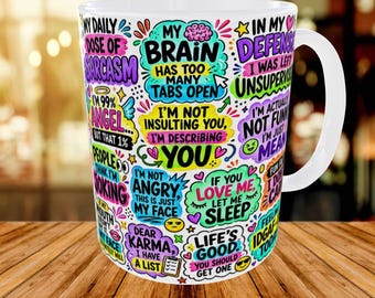 May include: A white ceramic mug featuring a colorful collage of various sarcastic phrases and doodles. Text includes My Brain Has Too Many Tabs Open, I'm Not Insulting You I'm Describing You, In My Defense I Was Left Unsupervised, and Life's Good.