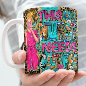 Può includere: Una tazza in ceramica bianca con un design colorato che presenta un'infermiera dei cartoni animati, simboli medici e il testo "This Nurse Needs Coffee".