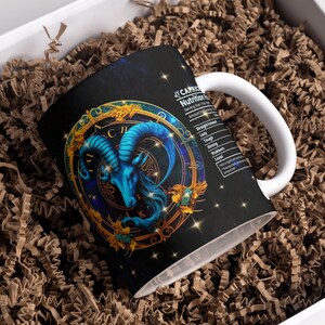 May include: A white ceramic mug with a black and gold design featuring a blue ram's head with horns. The mug has a black background with gold stars and a gold circle around the ram's head. The text "CAPRICORN" is printed on the mug, along with a list of "Nutritional Facts" for the zodiac sign.